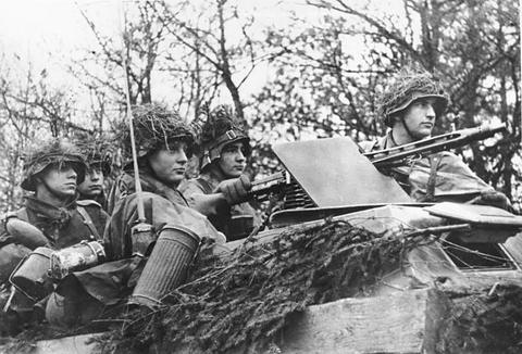 Period photograph: German soldiers in camouflage and helmet covers on a half-track
