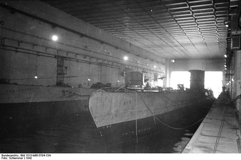 Period photograph: a submarine lying in a narrow dock under a massive concrete ceiling