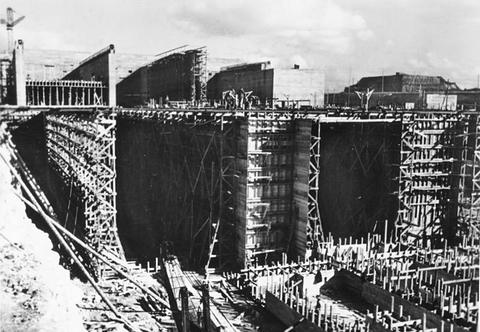 Period photograph: high concrete walls with timber scaffolding and bars of reinforcing steel