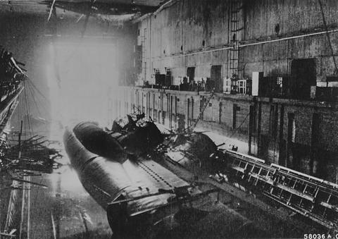 Period photograph: two wrecked submarines in a dock inside a damaged concrete hall