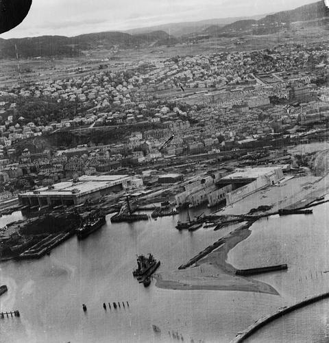 Period photograph: aerial view of a town and harbour, large bunkers on the waterfront