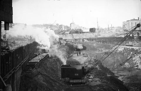 Period photograph: a building site with steam machinery and earthworks beside the water