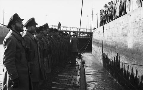 Period photograph: a submarine coming alongside, its crew in leather jackets standing in a line on deck