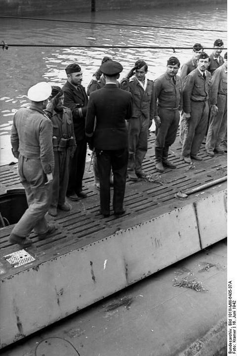 Period photograph: sailors in caps and leather jackets greeting each other on the deck of a submarine