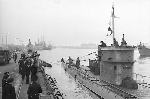 Period photograph: the conning tower of a submarine with crew members, seen from a quay
