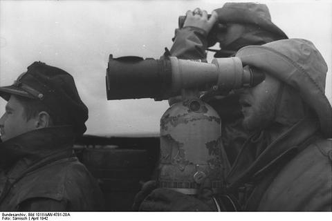 Period photograph: sailors in oilskin hats on a submarine bridge, one looking through binoculars