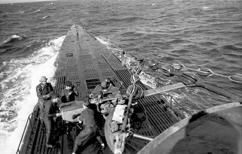 Period photograph: sailors handling a deck gun on the wet foredeck of a submarine at sea