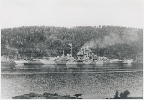 Period photograph: a battleship lying in a narrow fjord close to a wooded shore