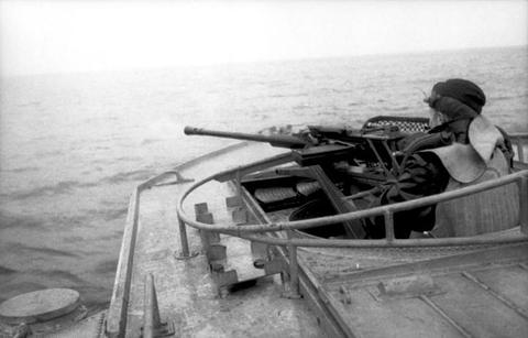 Period photograph: a sailor manning a gun on the bow of a fast boat at sea