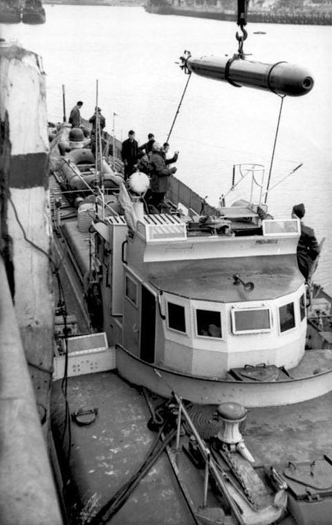 Period photograph: a torpedo hoisted by crane over the deck of a motor torpedo boat