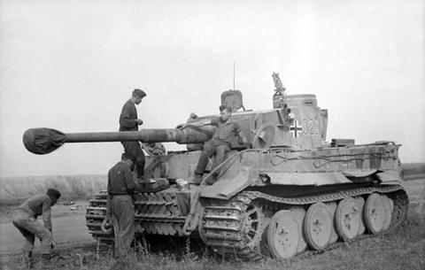 Period photograph: a Tiger tank with a cross on the turret, soldiers on the hull and beside the tracks