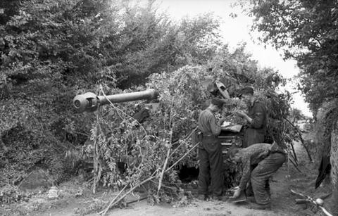Period photograph: crewmen standing in front of a Tiger I tank covered with branches