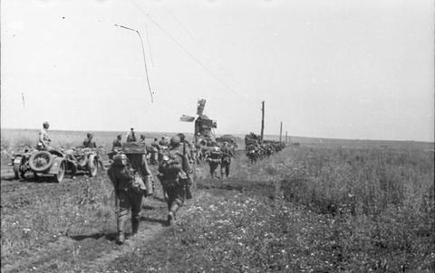 Period photograph: soldiers and vehicles moving along a rutted track across open country