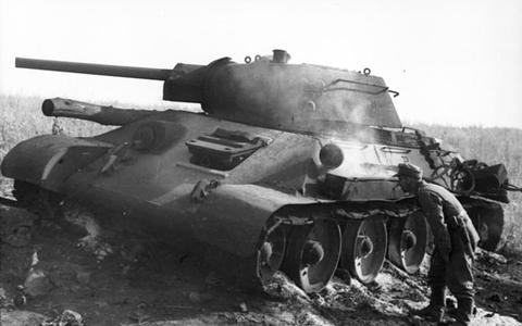 Period photograph: a soldier beside a damaged T-34 tank in a field