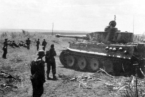 Period photograph: soldiers walking across a field towards a Tiger tank