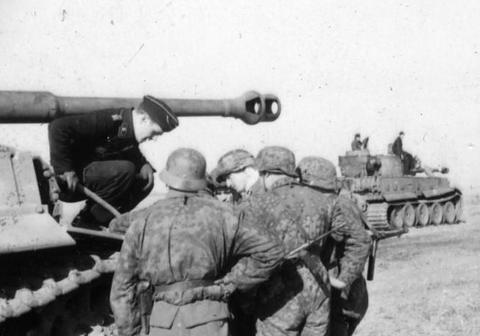Period photograph: soldiers in camouflage gathered at a tank, another Tiger behind