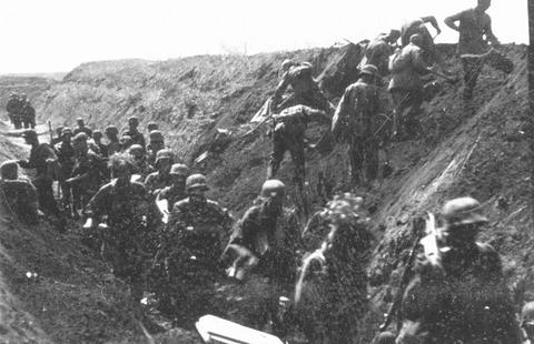 Period photograph: many soldiers crowded on the slope of a deep gully