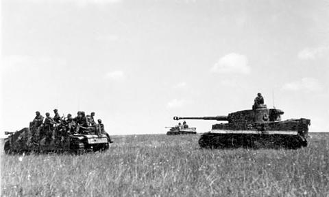 Period photograph: soldiers on a vehicle next to a Tiger tank in a wide grass field