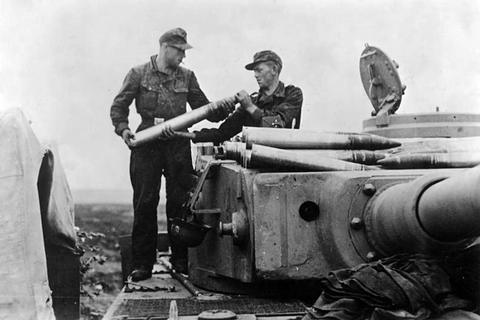 Period photograph: two crewmen handing tank shells across a Tiger tank