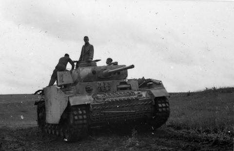 Period photograph: a tank with side armour on open ground, crewmen standing on it