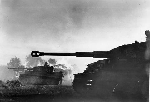 Period photograph: tank silhouettes against smoke from burning buildings