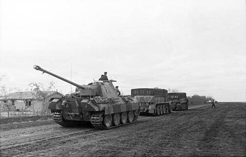 Period photograph: a Panther tank and two large half-tracks on a dirt road
