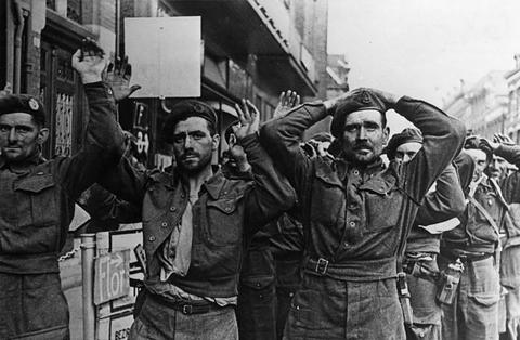 Period photograph: men in British uniforms with raised hands in a street