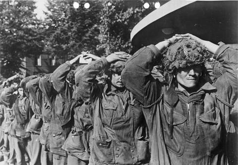 Period photograph: rows of soldiers with their hands on their heads
