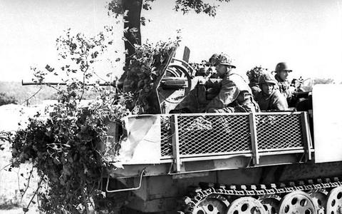 Period photograph: soldiers sitting in an armoured half-track heaped with branches