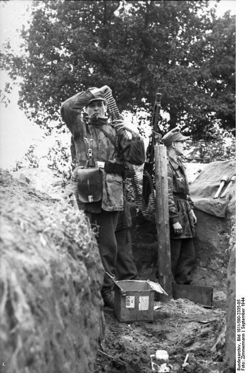 Period photograph: two soldiers standing in a trench under a tree, one shading his eyes