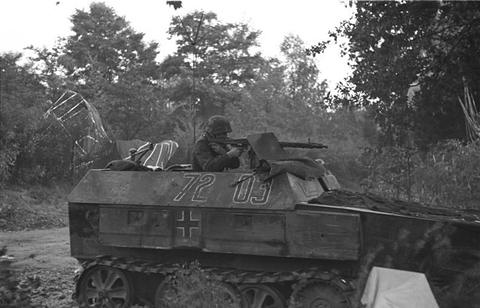 Period photograph: a light half-track with a cross on its side, a gunner on top