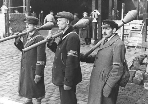 Period photograph: three older men in civilian coats with armbands, each holding a Panzerfaust
