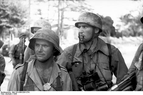 Period photograph: paratroopers in jump helmets, one with a pipe in his mouth