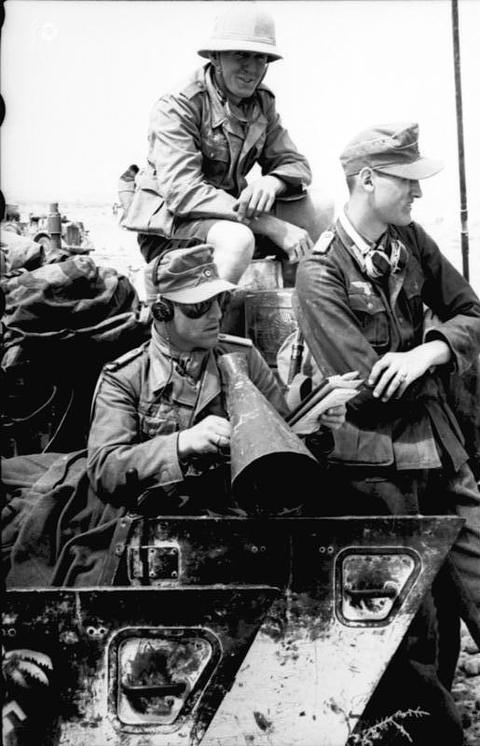 Period photograph: soldiers in tropical caps on a vehicle, one holding a megaphone