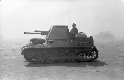 Period photograph: a small tracked vehicle with a gun shield on sandy ground