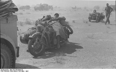 Period photograph: two men slumped asleep on a motorcycle with sidecar in the desert