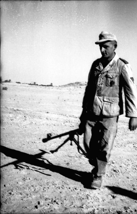 Period photograph: a soldier in a tropical cap walking with a long rifle