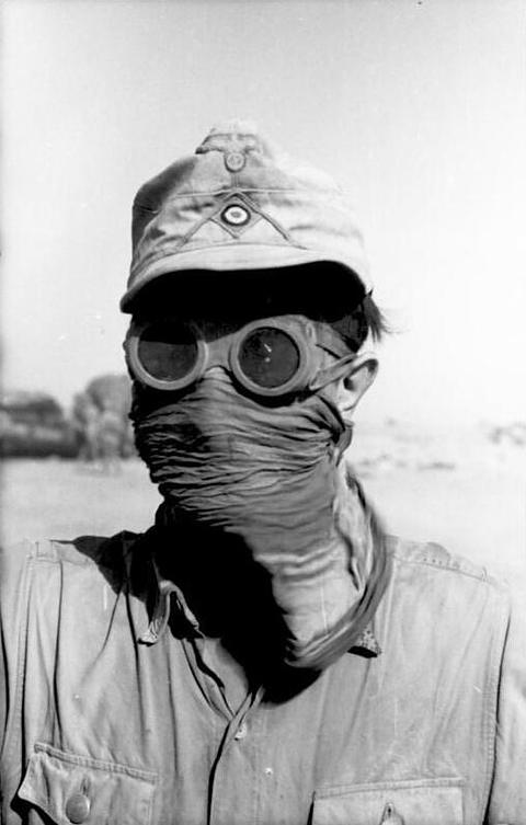 Period photograph: a soldier in a peaked cap, goggles and a cloth over his face