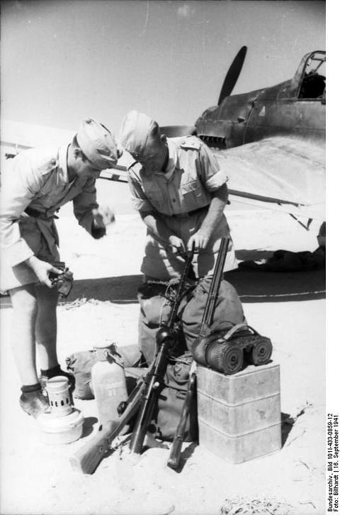 Period photograph: two men in shorts unpacking equipment beside an aircraft