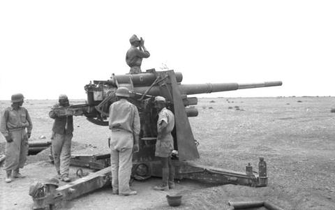 Period photograph: a large gun with soldiers around it, one on top using binoculars