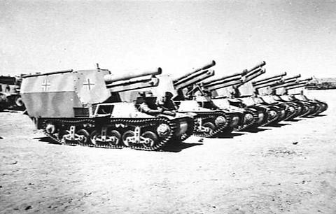 Period photograph: a line of tracked self-propelled guns parked in the desert