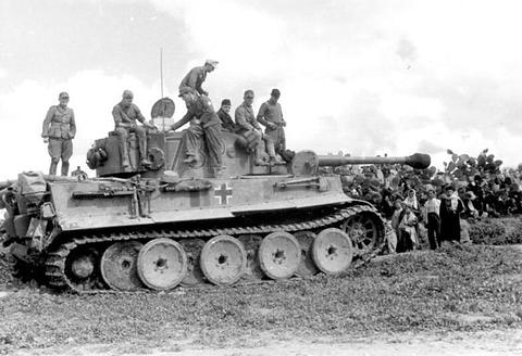 Period photograph: crewmen sitting on a Tiger tank beside a hedge of cactus