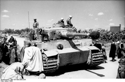 Period photograph: a Tiger tank in a street with soldiers aboard and people gathered round