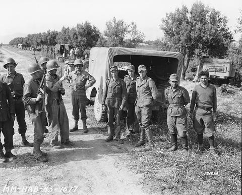 Period photograph: German and American soldiers standing together on a farm track beside a truck