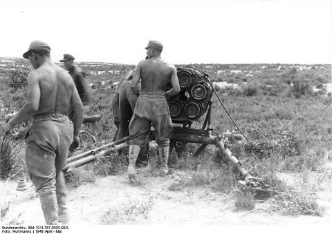 Period photograph: two soldiers in shorts loading a multi-barrel launcher
