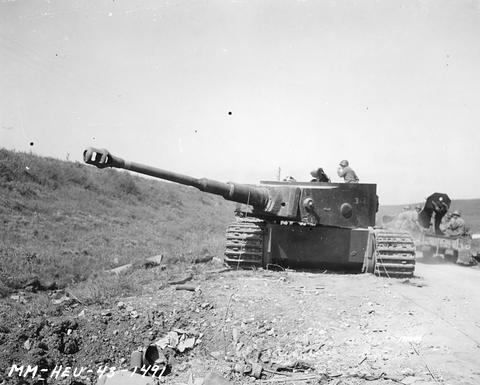 Period photograph: a Tiger tank beside a road, an American half-track passing