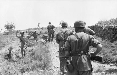 Period photograph: paratroopers escorting captured soldiers along a hillside track