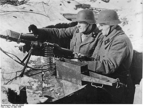 Period photograph: two men in steel helmets and greatcoats behind a machine gun in a snowy hole