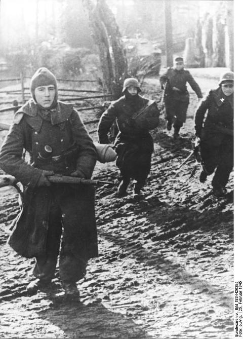 Period photograph: soldiers walking along a snowy village street, a tank behind them