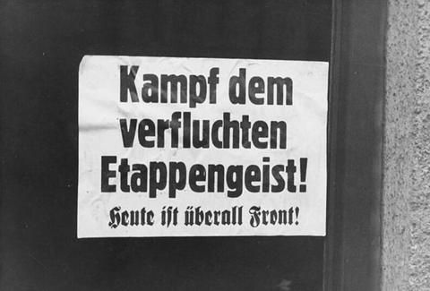 Period photograph: a printed text poster pasted on a dark wall